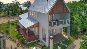 Una casa moderna de dos pisos con techo inclinado, ventanas amplias y una terraza de madera.