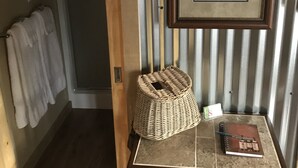 Un couloir avec un panier en osier posé sur une petite table, un tableau encadré et un porte-serviettes.