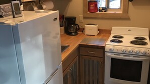 Une cuisine compacte équipée d’un réfrigérateur, d’une cuisinière et d’une machine à café.