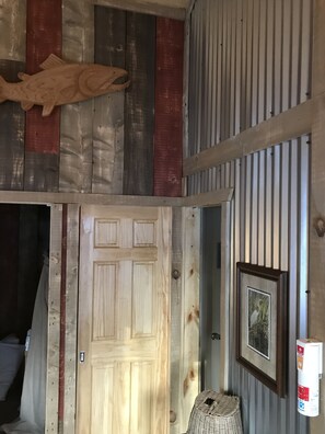 Une pièce avec une porte en bois, un tableau encadré accroché au mur et un poisson décoratif fixé au-dessus de la porte.