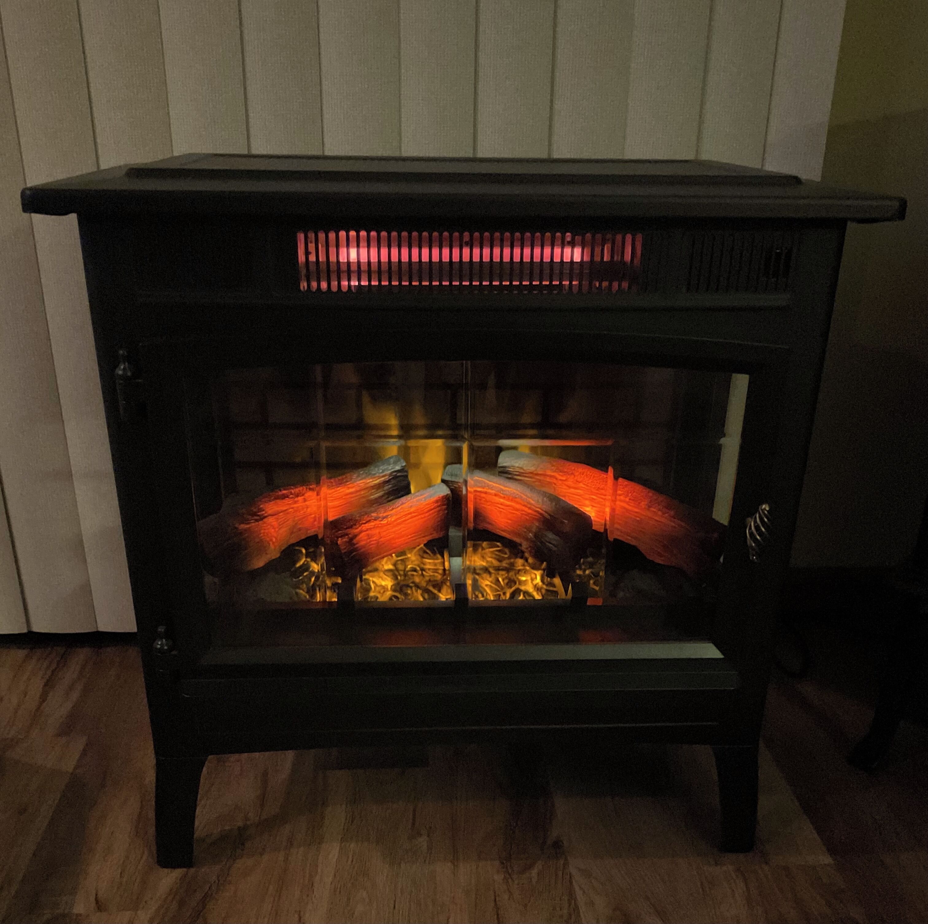 A black wood-burning stove with a glass front, displaying burning logs.