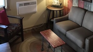 Un salon avec un canapé, une petite table, une lampe et deux tableaux encadrés accrochés au mur.