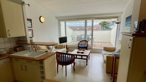 Cocina compacta con comedor, televisor y vistas al exterior.