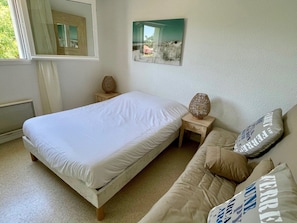 Ein Schlafzimmer mit Bett, Nachttisch, Lampe, Sofa und einem Gemälde an der Wand.