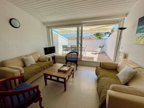 A living room with a sofa, armchairs, a coffee table, and a TV. There is a sliding glass door leading to an outdoor area. - Lovely apartment with terrace in Cap Ferret A0312 (Lège-Cap-Ferret)