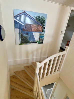Eine Treppe mit weißer Brüstung führt zu einem Raum, in dem ein Haus an der Wand hängt.