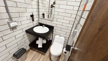 Une petite salle de bain avec un lavabo blanc, un plan de toilette noir et des toilettes blanches.