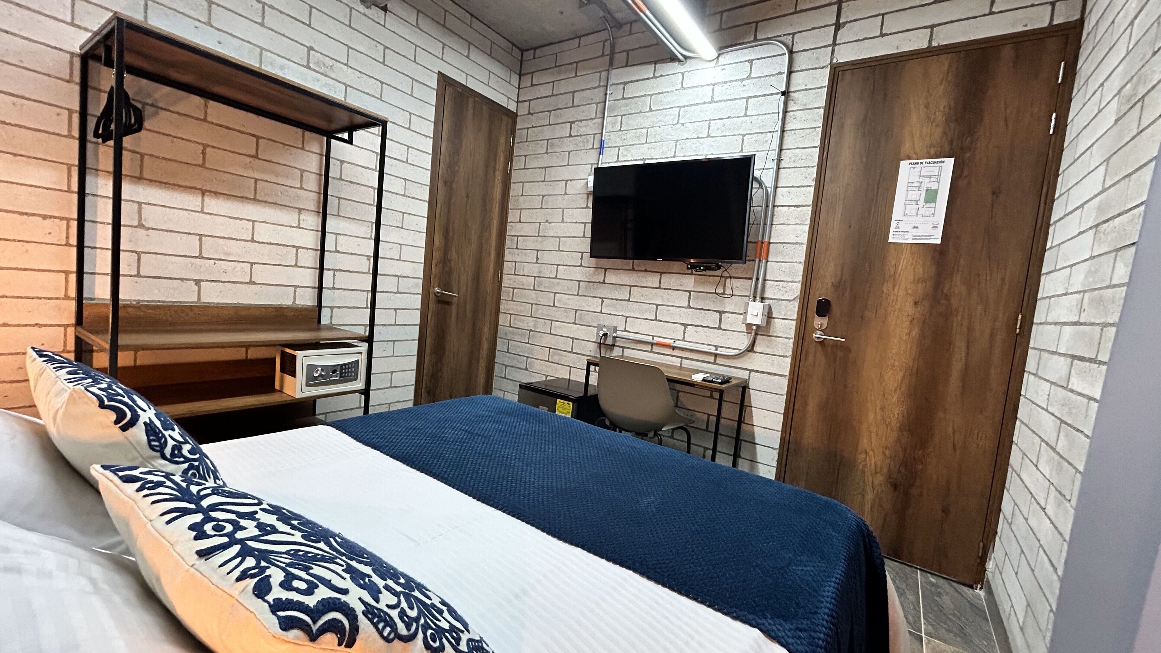 Hotellihuone, jossa on sänky, työpöytä, tuoli, televisio ja vaatekaappi.