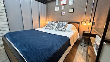 Un dormitorio moderno con una cama grande, una mesita de noche con lámpara y una pared decorada con cuadros.
