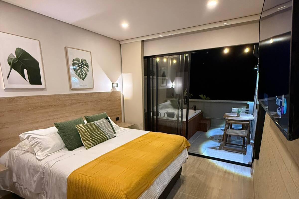 Un dormitorio moderno con una cama grande, un balcón con puerta de cristal y obras de arte en las paredes.
