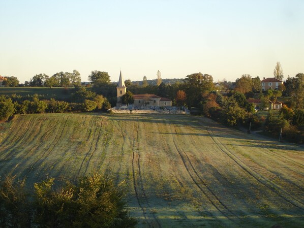 Paisaje rural con una iglesia, campos y casas dispersas.