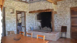 Interior rústico de piedra con chimenea, muebles de madera y pared de piedra.