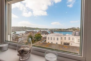 A window view of a coastal town with buildings, a pier, and a clear sky. - Magnificent views of Tamar and Rwy. Free Parking (Plymouth)