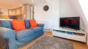 Una sala moderna con un sofá, un televisor de pantalla plana y un mueble blanco para entretenimiento.