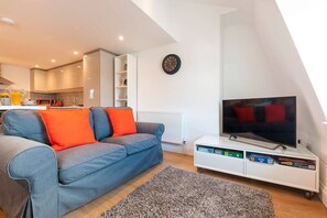 A modern living room with a sofa, a flat-screen TV, and a white entertainment unit. - Magnificent views of Tamar and Rwy. Free Parking (Plymouth)