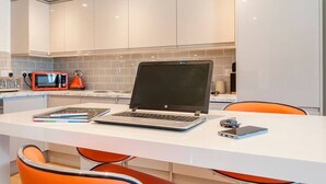 Una cocina moderna con armarios blancos, encimera blanca y un ordenador portátil.