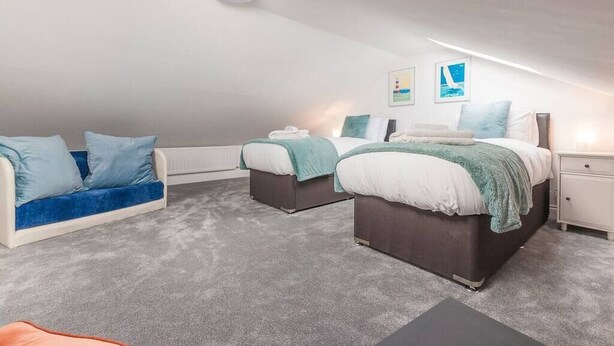 Un dormitorio con dos camas, un sofá y una mesita de noche.