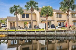 A row of two-story houses with a dock extending into a calm body of water.