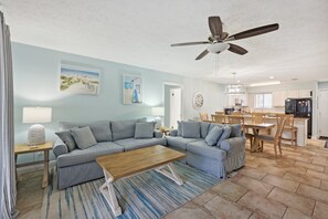 A living room with a sectional sofa, a wooden coffee table, and a ceiling fan.