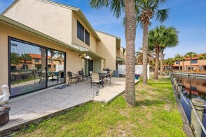A modern house with a patio, outdoor furniture, and a view of a canal.