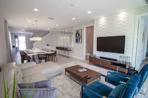 Relax in a spacious living area with a large TV, comfortable seating, and a dining table.