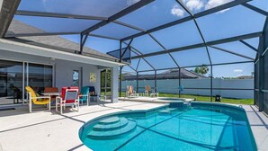 A covered outdoor swimming pool with lounge chairs and a patio area.