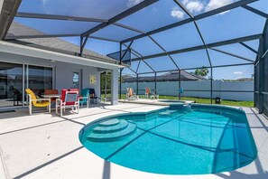 A covered outdoor swimming pool with lounge chairs and a patio area.