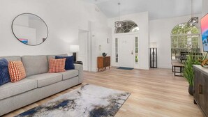 A living room with a grey sofa, round mirror, and a large rug.