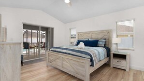 A bedroom with a wooden bed, a nightstand, a ceiling fan, and a view of an outdoor patio.