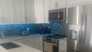 A modern kitchen with white cabinets, a stainless steel refrigerator, a microwave, and a built-in oven. - Beautiful waterfront 3/2 home with dock and boat lift. Cabana Club included! (Key Colony Beach)