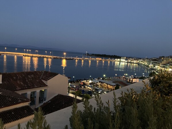 A coastal town at dusk with a marina, waterfront buildings, and a prominent pier.