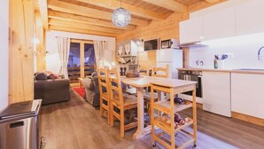 Una cocina compacta con muebles de madera, una mesa de comedor, sillas y un refrigerador pequeño.