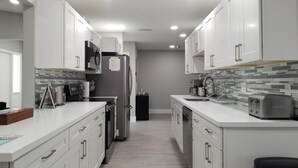 A modern kitchen with white cabinetry, a black refrigerator, a toaster, and a coffee maker. - 3-Bedroom Heated Private Pool Vacation Home just minutes from the Beach Pet (Deerfield Beach)
