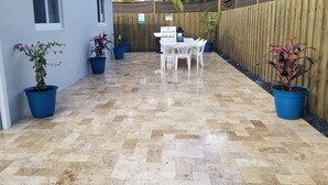 A patio area with a tiled floor, a white table with chairs, and potted plants. - 3-Bedroom Heated Private Pool Vacation Home just minutes from the Beach Pet (Deerfield Beach)