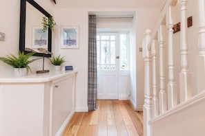 A hallway with a white door, a mirror, and framed pictures on the wall.