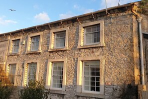 Ein Gebäude aus Stein mit mehreren Fenstern und einem sichtbaren Rohr auf der rechten Seite.