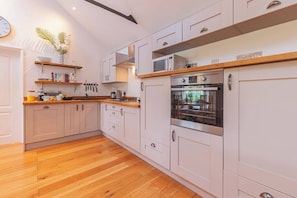 A modern kitchen with white cabinetry, a wooden countertop, and stainless steel appliances.