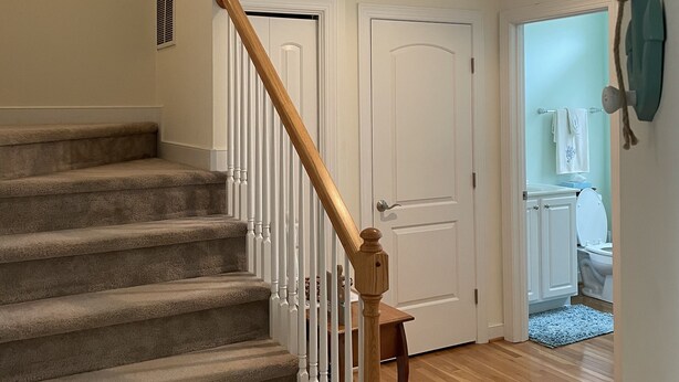 A staircase with carpeted steps and wooden handrails, leading to a door. - Beautiful beach bliss (Ocean View)