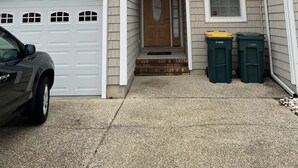 A two-story house with a garage, a front door, and two trash bins. - Beautiful beach bliss (Ocean View)