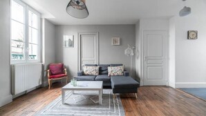 Una sala de estar moderna con un sofá gris, una butaca roja, una mesa de centro blanca y una alfombra estampada.