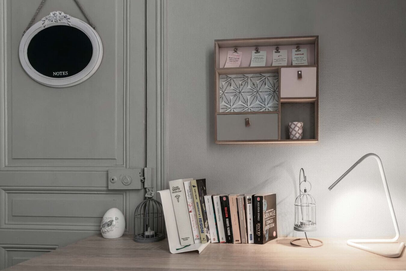 Un espace de travail comprenant un bureau, des livres, une lampe, un tableau pour les notes et un objet décoratif.