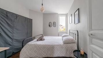 Una camera da letto con un letto, un tavolino, una finestra e una porta.