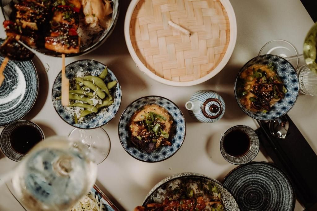 A table with various dishes and bowls, some with lids, and a few glasses.