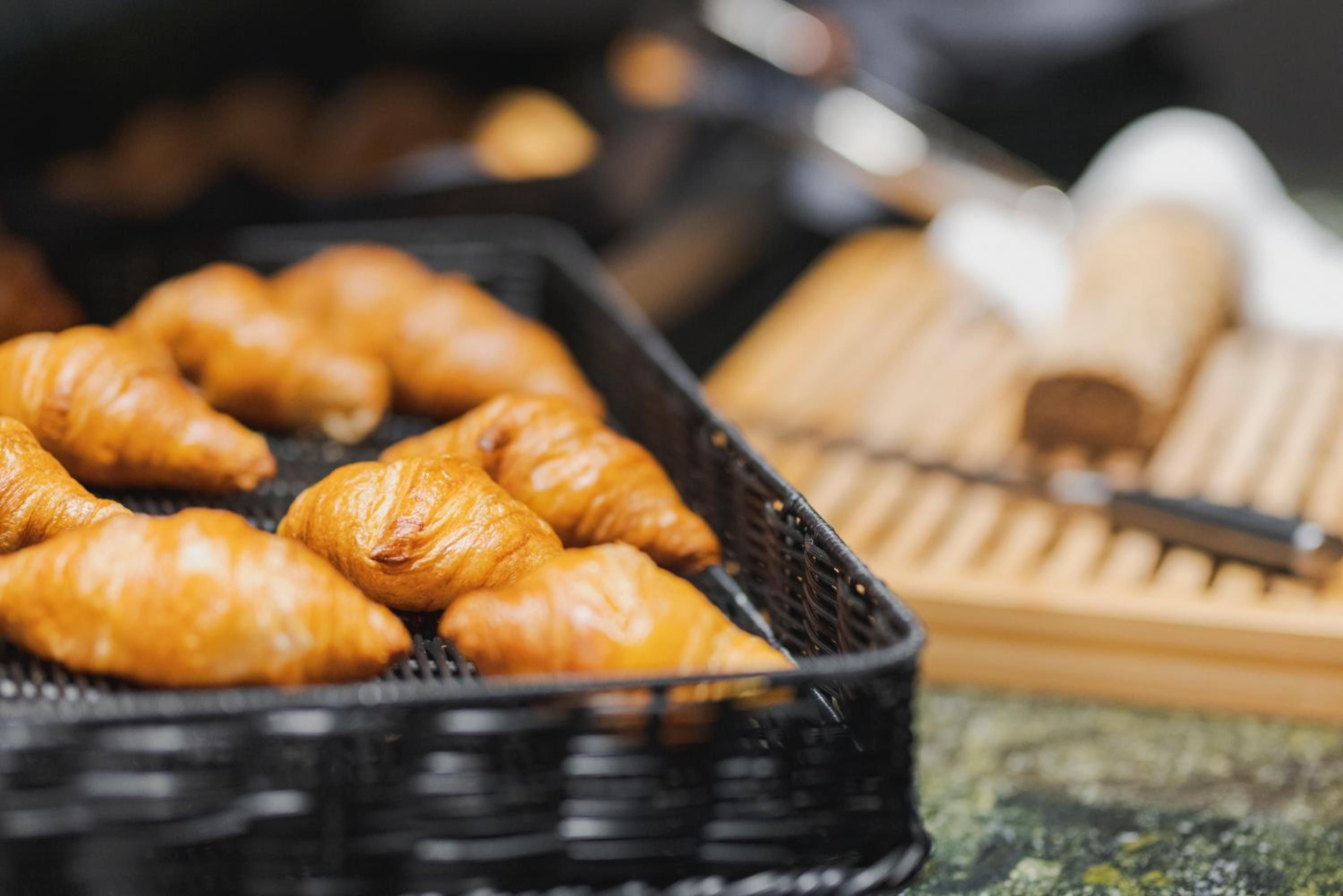 A tray of golden-brown pastries, likely croissants, in a black basket.