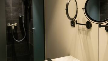 A modern bathroom with a white sink, two mirrors, and a shower area.