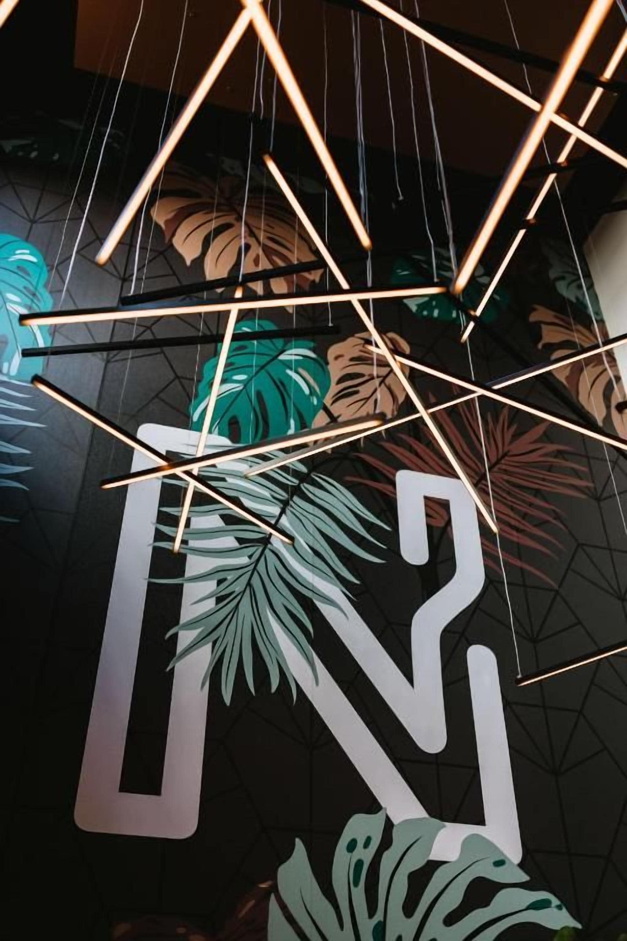 A geometric light fixture with intersecting lines and a large, stylized letter 'N' in the foreground.