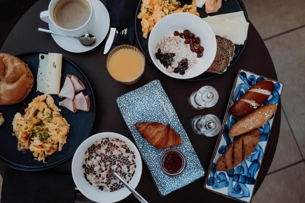 Een ontbijtsetting met diverse gerechten en een kop koffie op een ronde tafel.