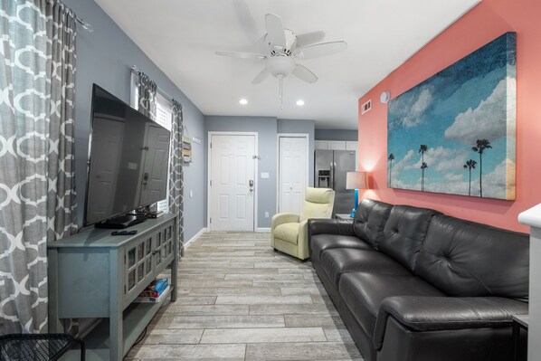 A living room with a TV, sofa, and ceiling fan.