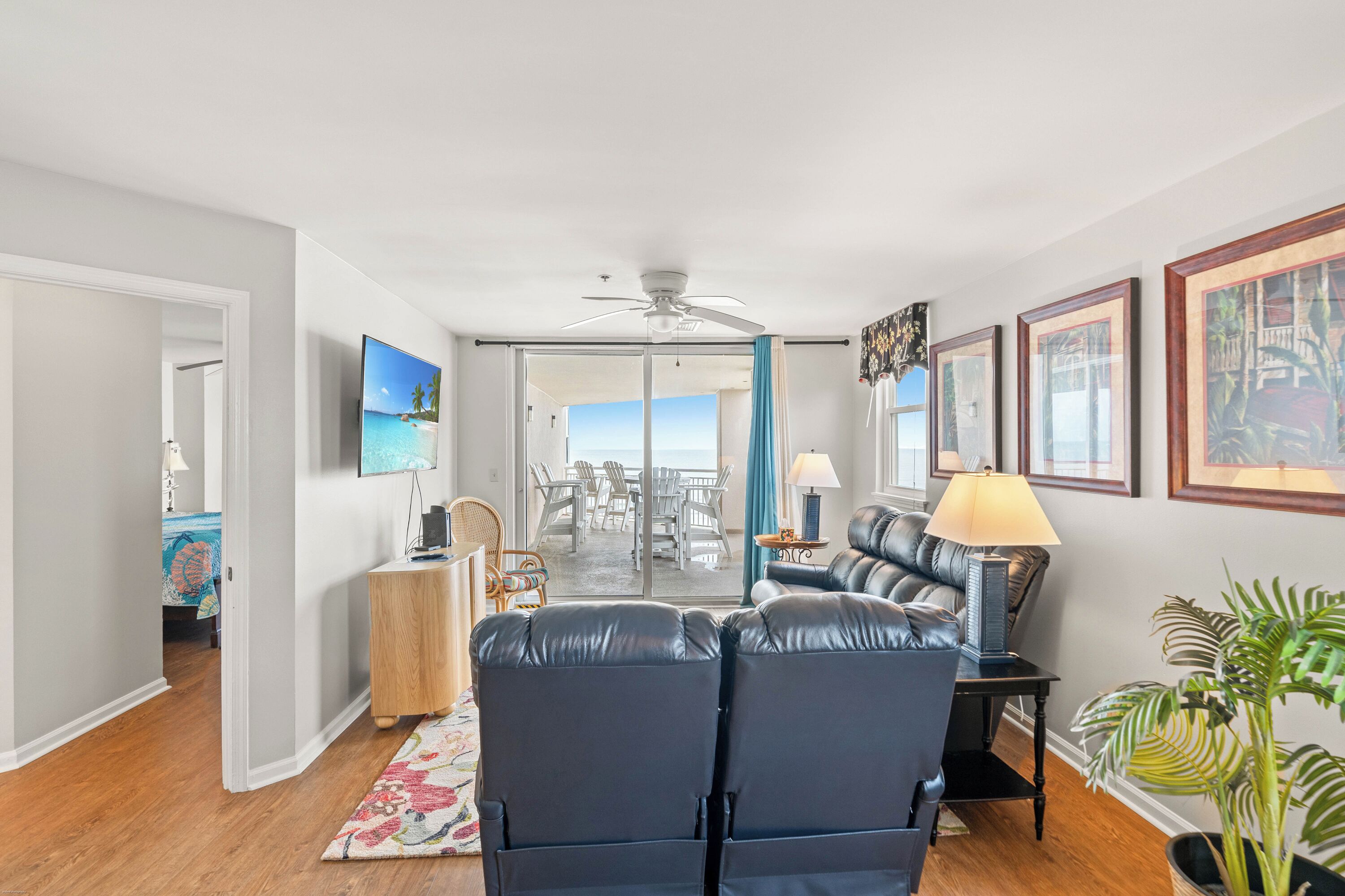 A modern living room with a leather sofa, a flat-screen TV, and a view to the outside.