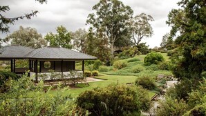 A modern pavilion with a sloped roof, surrounded by well-maintained gardens and trees. - Tiny Balloon House by Tiny Away (Canowindra)